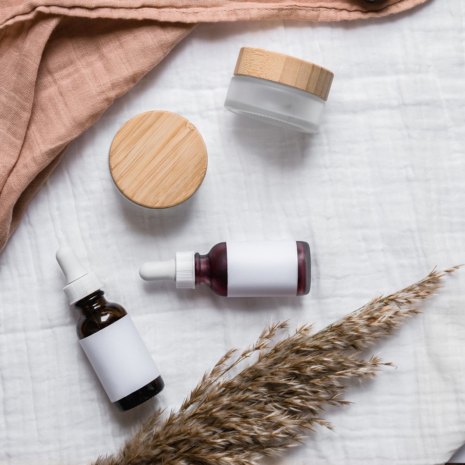 Stylish flat lay of serum bottles and jars on soft fabric with a natural, earthy aesthetic.