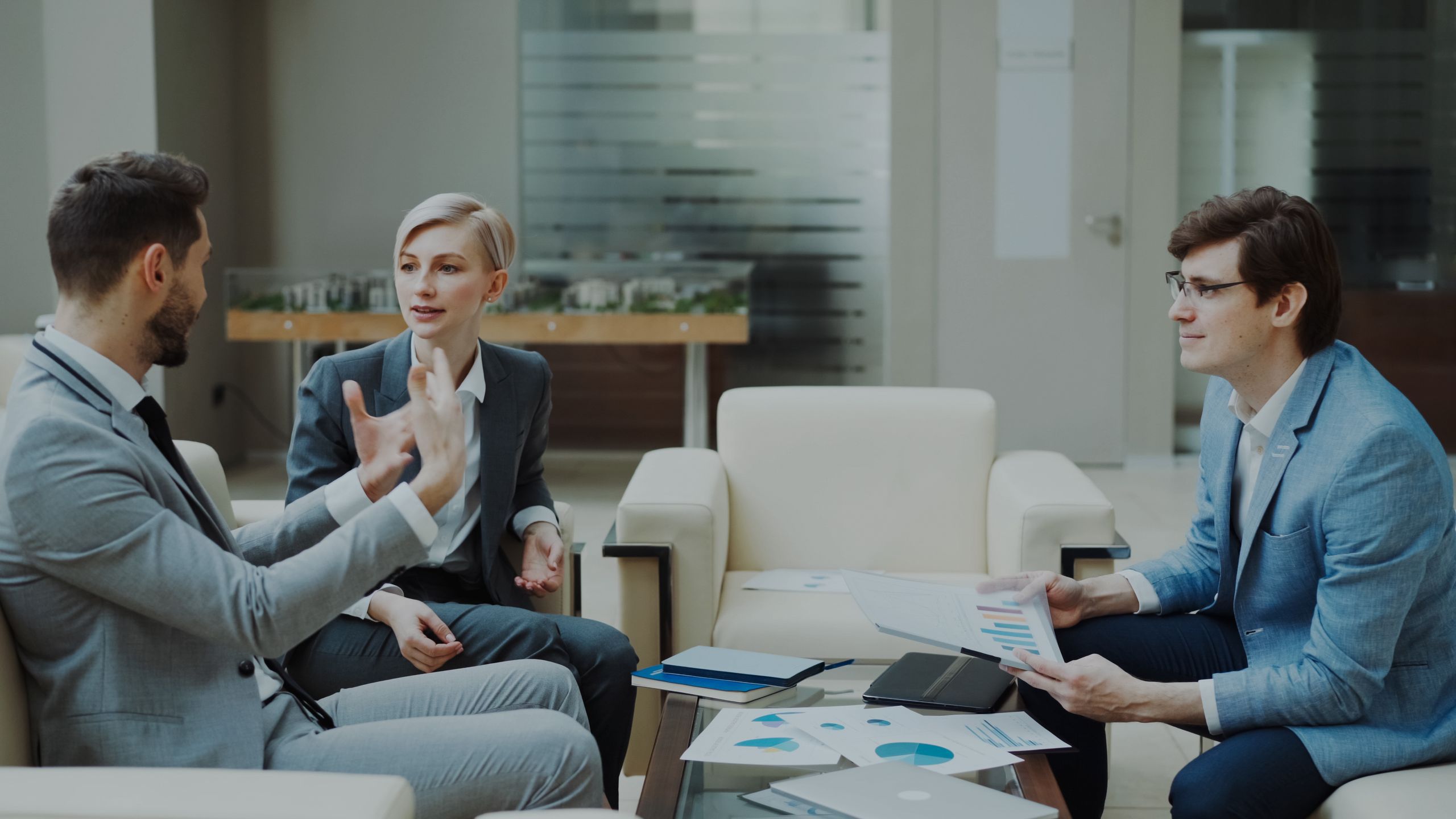 Three professionals engaged in a meeting with documents and charts in a modern office.